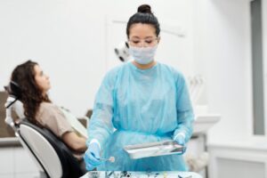 Dentist in protective gear preparing dental tools in a modern clinic.